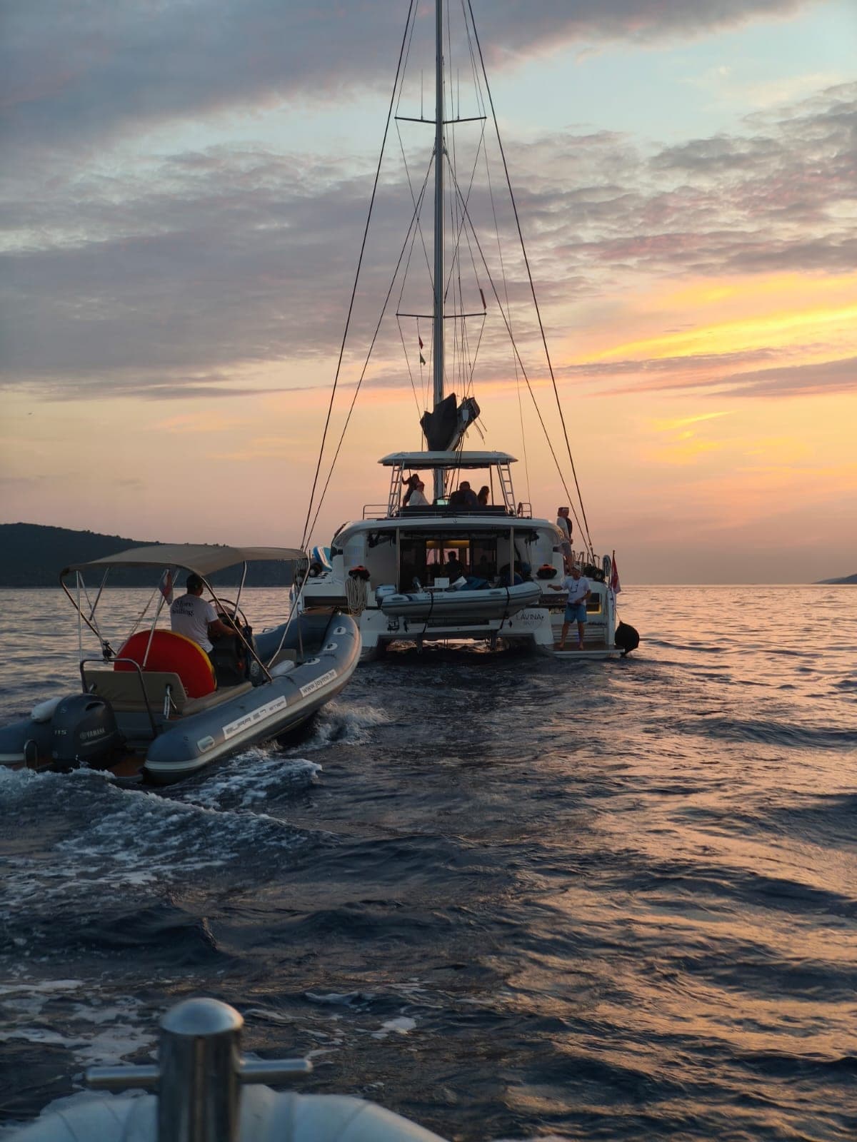 Bura tender towed behind a charter catamaran at sunset
